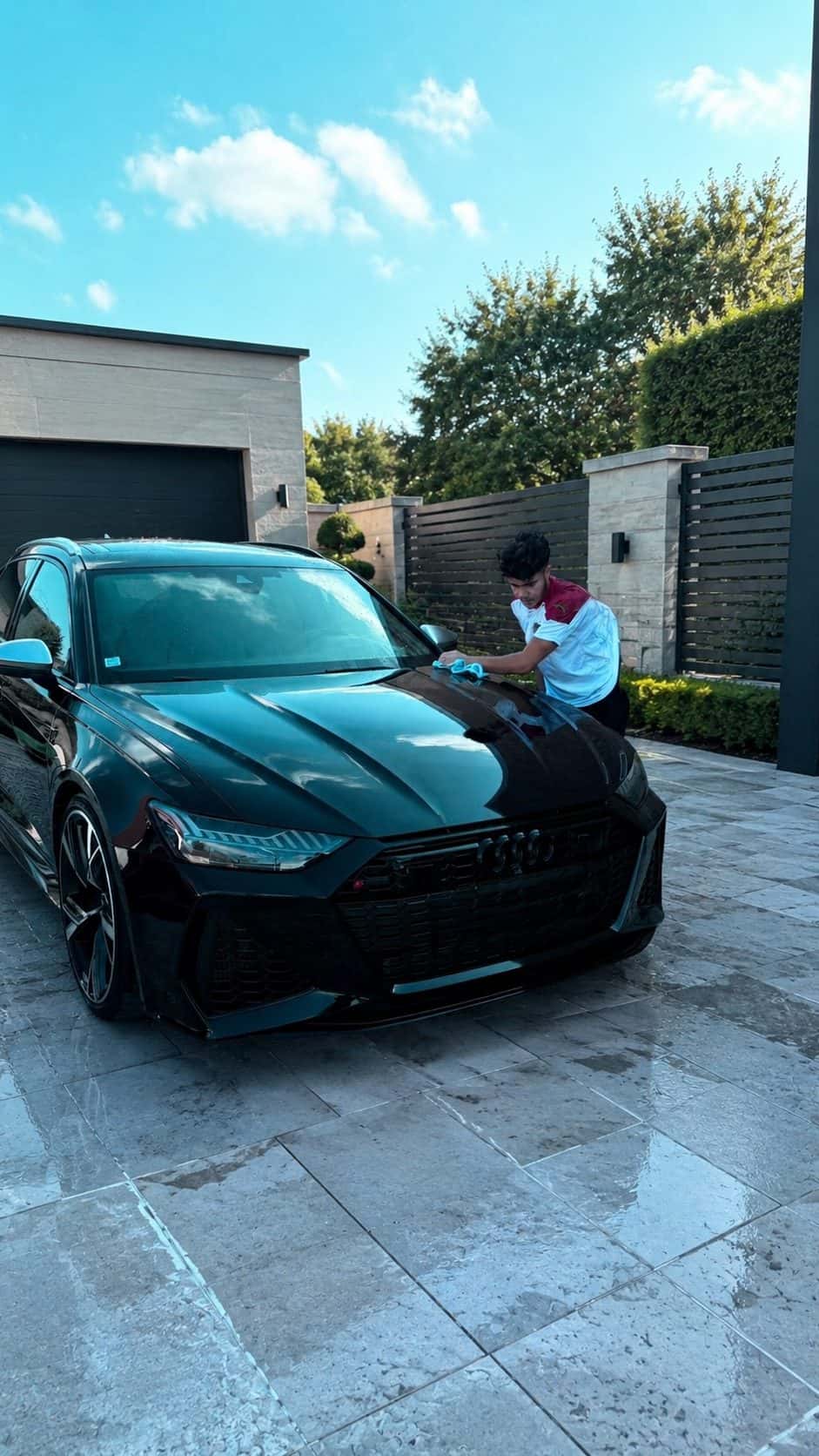 Kylian essuie à la main le capot d’une Audi RS6 noire